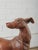A striking hand-carved wooden sculpture depicting a sleek greyhound in motion, captured mid-stride with elegant, elongated...