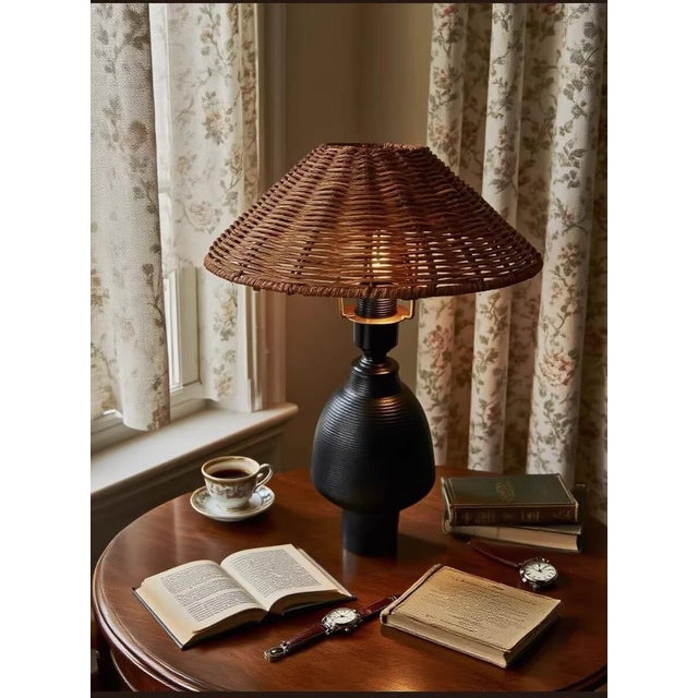 Shade is dark brown rattan (wide-brim woven texture, rich vintage feel), body is matte black textured ceramic + metal...