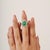 Featuring a oval cabochon emerald weighing 5.2 carats, The center stone is surrounded by a halo of accent stones weighing...