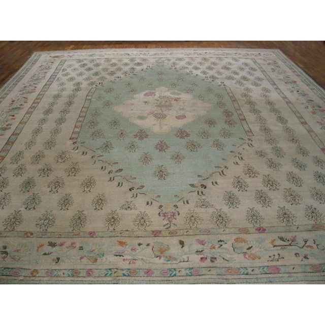 Ivory field, ivory border, generally very light tonality without being pastel make this squarish antique Oushak carpet...
