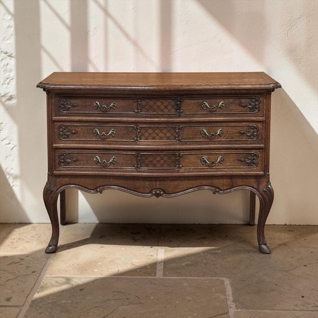 A Country French Régence style chest of drawers crafted in oak, with three serpentine drawers raised on graceful cabriole...