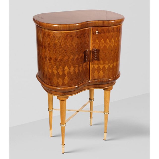 This Art Deco-style bar cabinet with swing doors features a refined burl wood structure with elegant metal details and a...