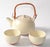This vintage Kotobuki tea set includes one top-handled teapot and two teacups each featuring a beige glaze and brown...
