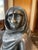 Pewter Sculpture of Seated Woman in Her Wrap. Marking. Sculpture sits on a wood base, 2 inches tall.