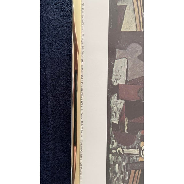 A vintage framed museum print reproducing Pablo Picasso’s 1918 Cubist oil painting “Still Life,” part of the permanent...