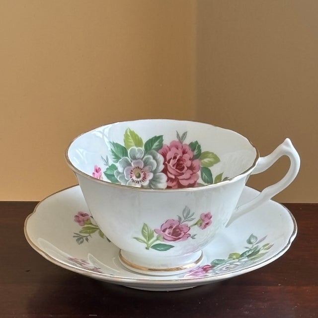 A charming mid-century English bone china teacup and saucer by Collingwoods, decorated with romantic pink roses and...