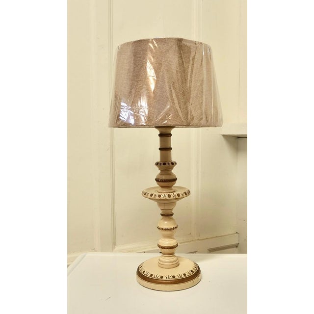 Folk Art Style carved and painted table lamp. This lamp has a carved decoration painted in cream with gold highlights, the...