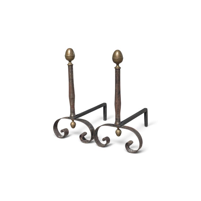 Antique heavy andirons. This pair of andirons are crafted out of wrought iron and brass. They feature acorn brass finals...