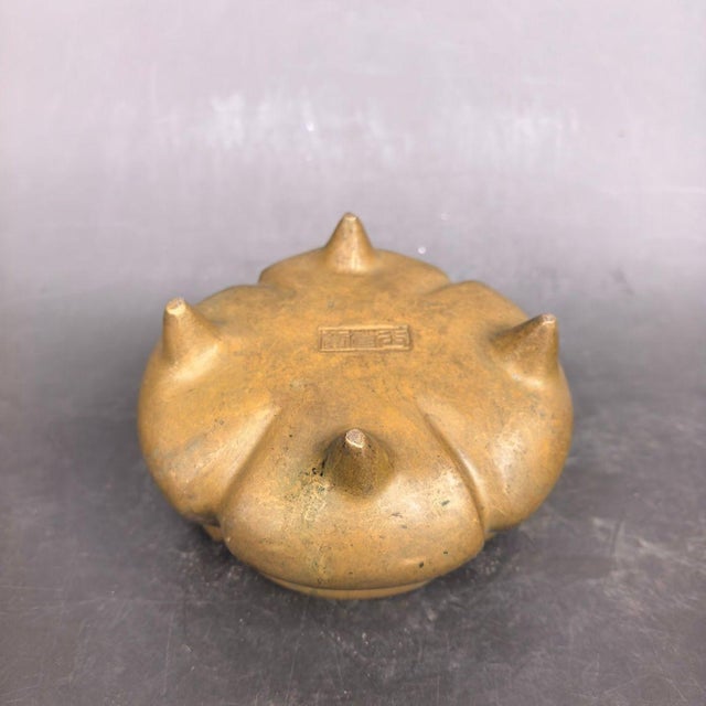 Traditional Chinese brass incense burner with melon lobed body, a pair of upright yuanbao (ingot) shaped handles and three...