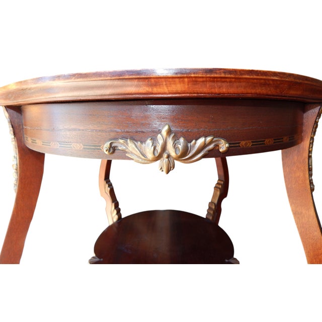 Intricate inlay, cast brass accents, and gilt painted accents combine to make this table from the early 20th century a...