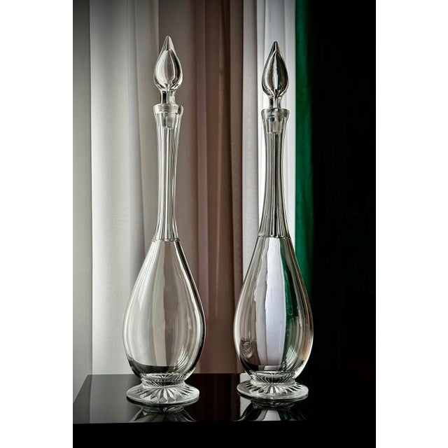A refined pair of antique clear glass decanters dating from the late 19th to early 20th century. Each piece has a tall...