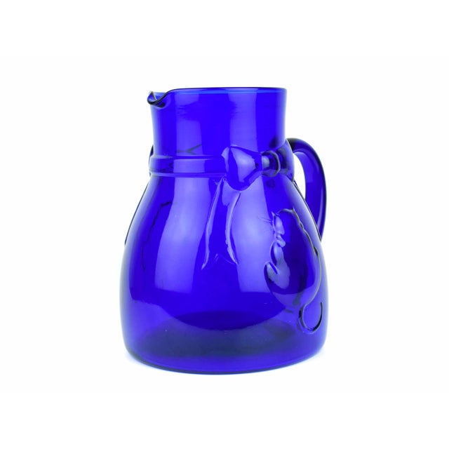 This striking Mid-20th Century Italian pitcher is a vibrant example of vintage cobalt blue glassware, combining playful...