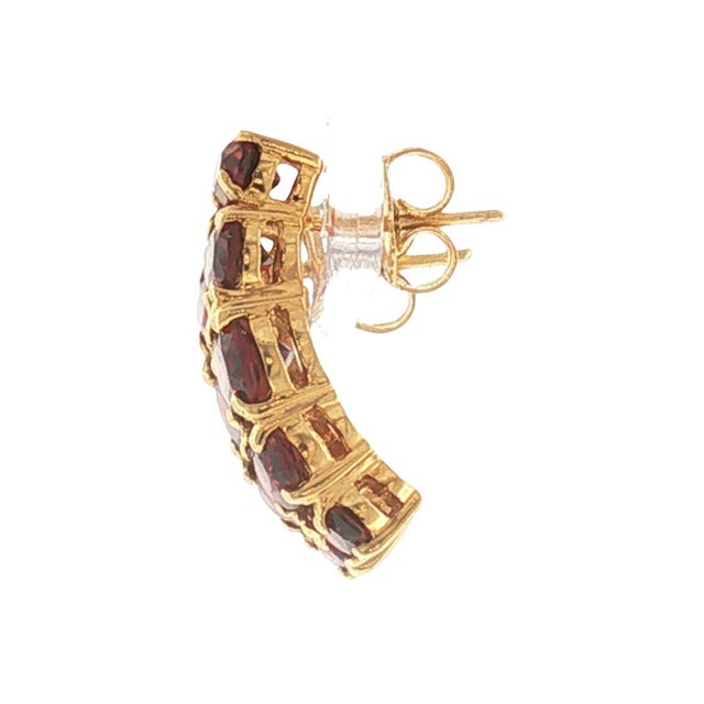 A striking pair of modern vintage half hoop earrings featuring garnet stones. Crafted in 14k gold, these earrings showcase...