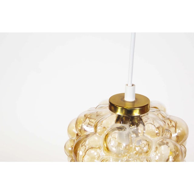 Cute amber colored bubble pendant light. Designed by Helena Tynell for Glashutte Limburg in Germany during the 1960’s. In...