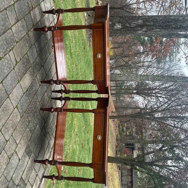 Pair 2 tier Italian walnut consoles. Each consoles with a center drawer brass pull raised on 4 fluted legs with stretcher.