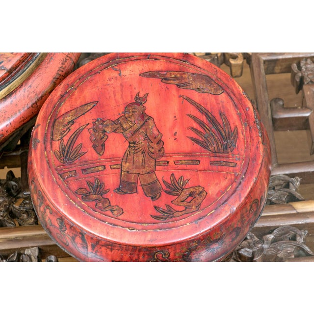 A pair of antique Chinese red lacquered covered boxes. The larger box has a domed lid painted with a traditional Chinese...