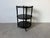 Elegant 1960s Hollywood Regency three-tier side table featuring a sophisticated black ebonized finish, turned spindle...