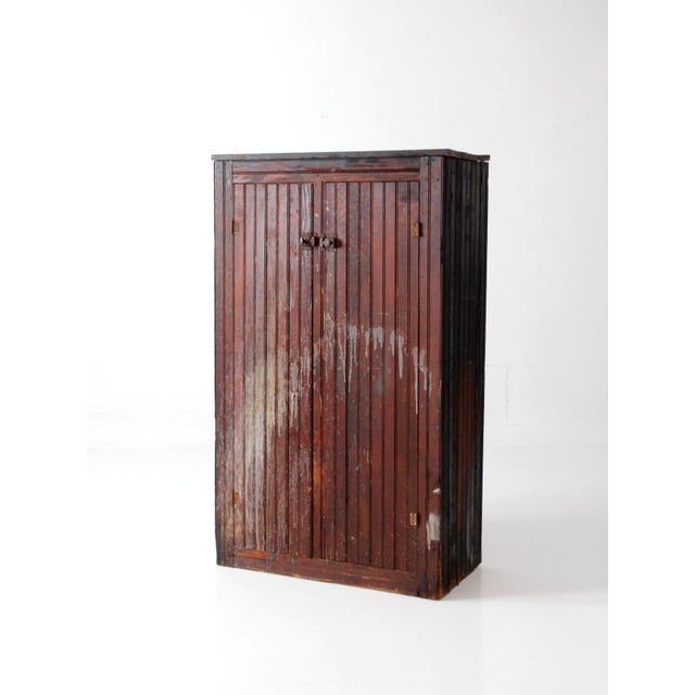 This late 19th century Primitive cabinet features tongue-and-groove board construction, paneled double doors, and original...