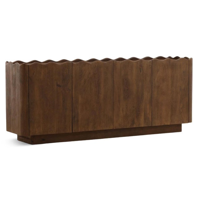 Sculptural solid mango wood four-door credenza with deeply carved wave-front facade and rich brown wood tones. The...