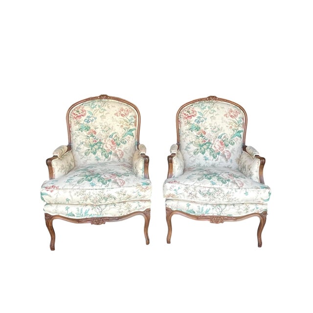 Charming pair of bergère accent chairs featuring a soft floral upholstery in delicate pastel tones. Crafted in a...