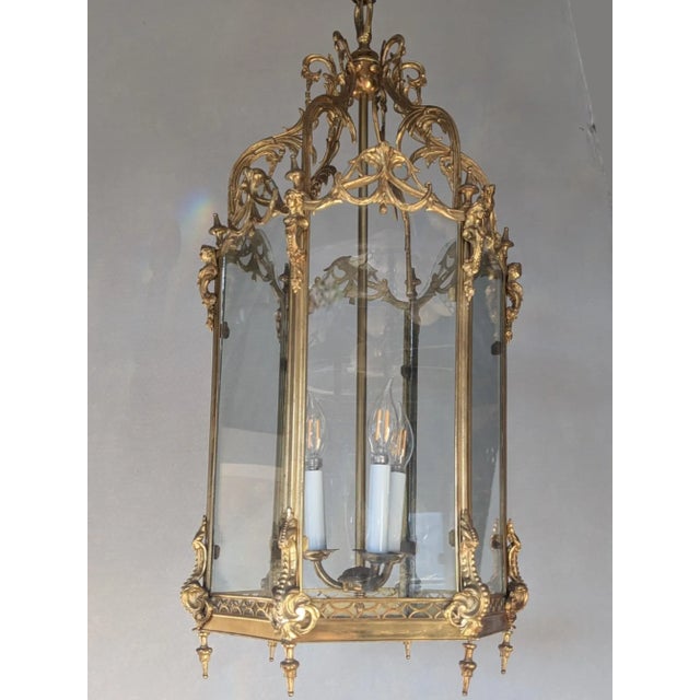 Petit Trianon style hexagonal polished brass hanging lantern. The lantern top is adorned with acanthus leaves and draped...