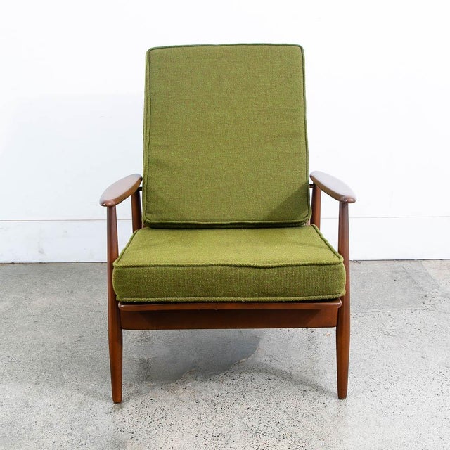 Mid century modern arm chair in solid wood and upholstered in a green fabric. Wood arms on either side. Wood frame fully...