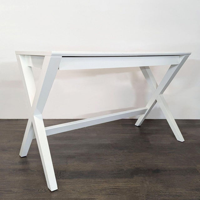 This Crate and Barrel desk features a sleek white finish and sturdy X-leg design, perfect for any home office or study...
