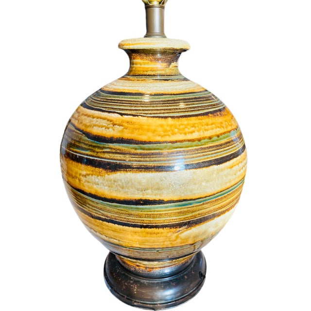A large 1960's Mid-Century Modern pottery table lamp with fat lava glaze in tones of brown, green, gold, and cream. The...