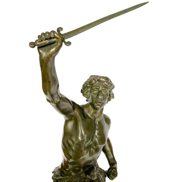 DETAILS An antique figural mantel clock in cast spelter with a bronzed finish. After sculptor Emile Laporte, the statue is...