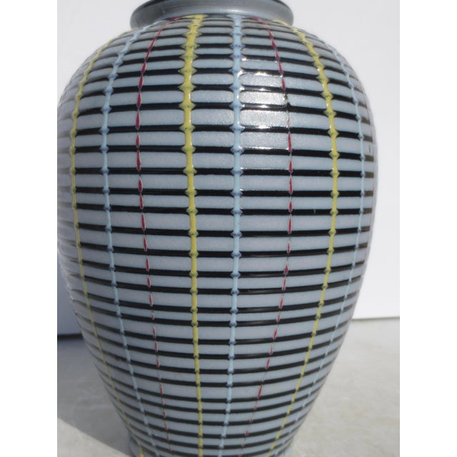 Studio vase in porcelain with 5 color glazes over sides. The interior is clean and the bottom is glazed in black....