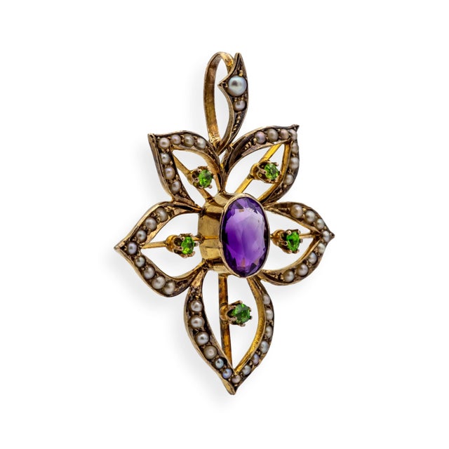 Antique pendant from the Edwardian and Art Nouveau period, featuring a flowing floral motif centered by a richly saturated...