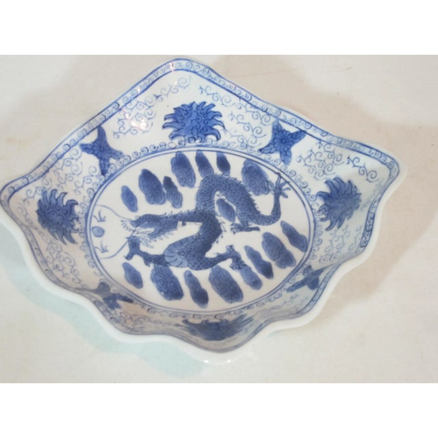 Hand painted blue and white Asian bowl decorated with a center dragon, clouds scrolls and flowers. It is square shaped...