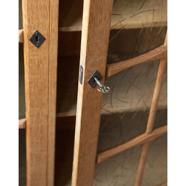 A tall Danish oak bookcase cabinet from the 1970s, with two glass-front doors and adjustable interior shelves — the kind...