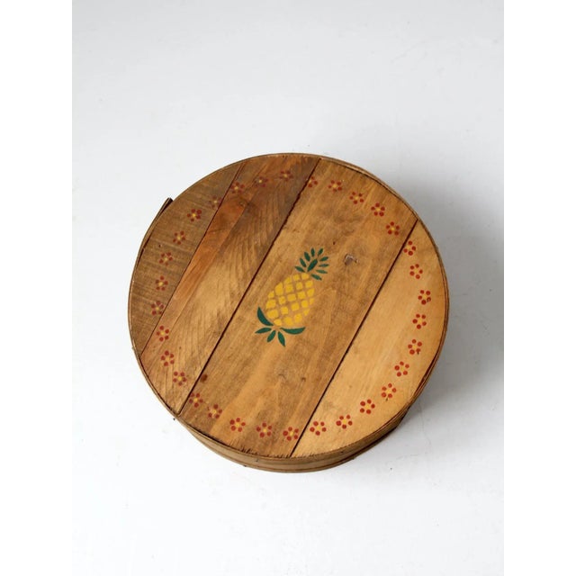 This is an old vintage wooden cheese box with stencil painted accents. The hand-crafted wood band box features pineapple...