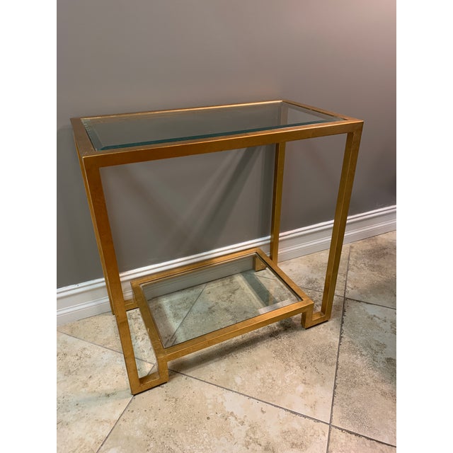 Versatile gold leaf glass console table has a chic and modern style. It has two simple glass shelves and an elegant gold...