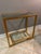 Versatile gold leaf glass console table has a chic and modern style. It has two simple glass shelves and an elegant gold...