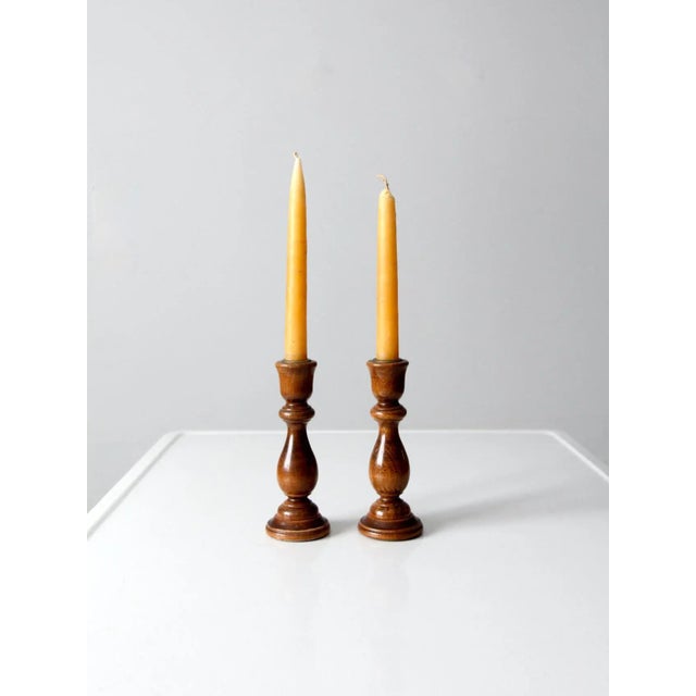 A charming pair of vintage turned wooden candlesticks, each designed to hold a standard taper candle. The gracefully...