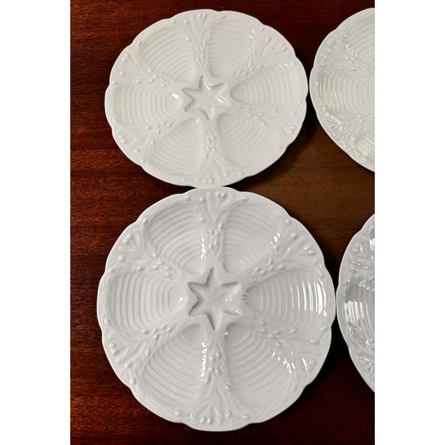 Here is a set of four bright-white porcelain oyster plates--made in France for DANSK INTERNATIONAL DESIGNS LTD. Each plate...