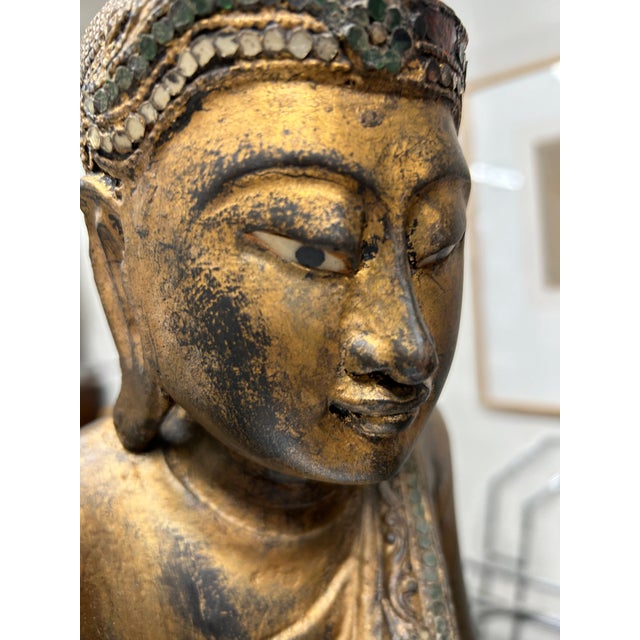 Classic Thai gilded wood standing Buddha in a serene pose, mounted on newer ebonized wood stand.