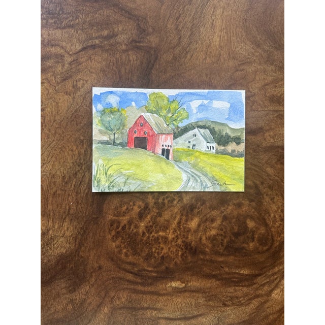 A cozy countryside escape comes to life in this vibrant watercolor featuring a striking red barn nestled among lush green...