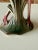 A charming pair of mid-20th century ceramic flamingo figurines featuring vibrant pink and green glazed finishes with...