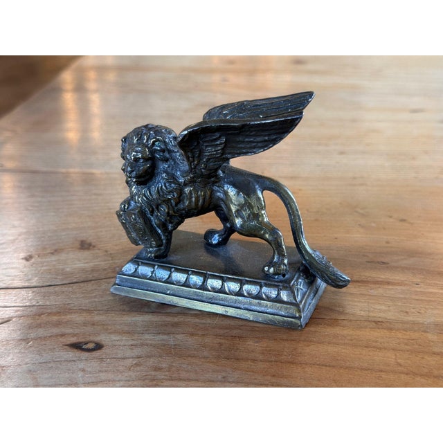 19th century English patinated white metal herald lion striding forward with wings raised, one forepaw on a book, head...