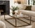 A handsome rectangular coffee table by Arhaus featuring a clean, architectural metal frame in a warm bronze finish with an...