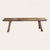 A sculptural rustic bench crafted from solid pine, featuring a thick plank seat supported by four splayed legs joined...
