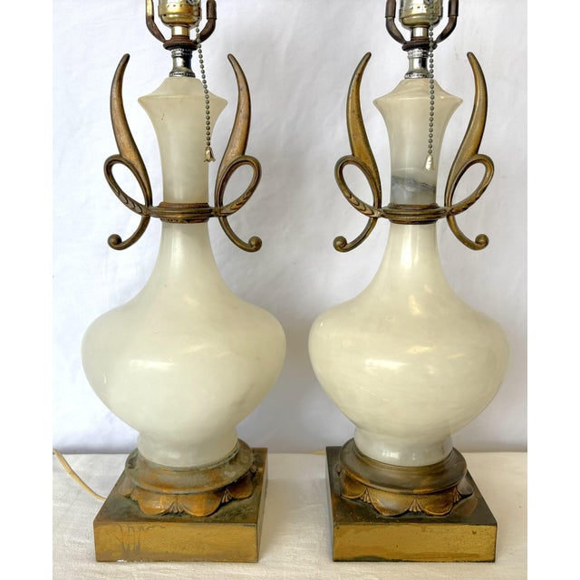 Striking pair of alabaster table lamps from the mid 20th century. These are made of heavy white alabaster with an urn...