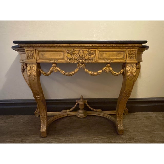 An elegant and generously scaled early-20th-century French Louis XVI-style console, finely carved in giltwood and...