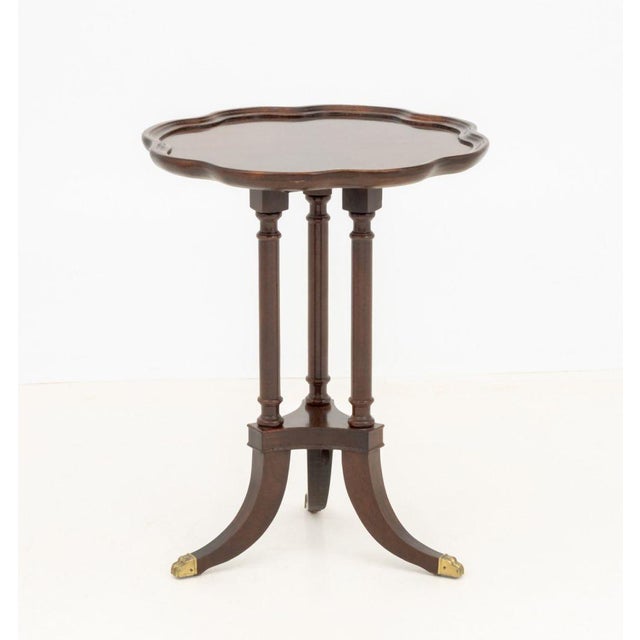 American Empire Style Mahogany Tripod Table, the shaped floriform top above three fluted legs terminating in brass lion's...