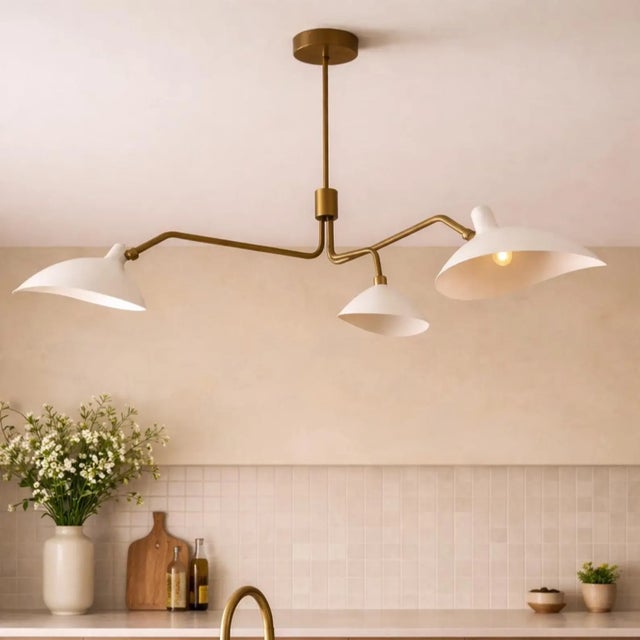 A handcrafted solid brass three-light chandelier featuring asymmetrical arms and white metal shades. Its balanced...