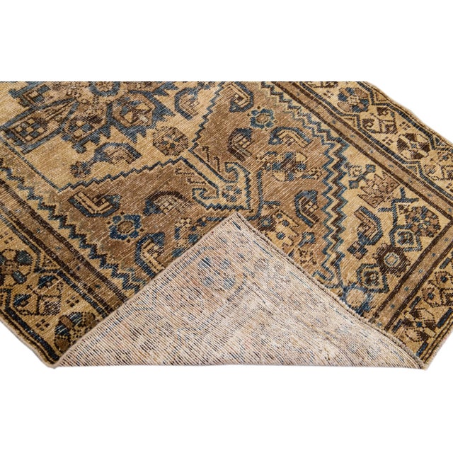 Beautiful vintage Persian distressed hand-knotted wool rug with a brown color field. This piece has a beige frame and navy...