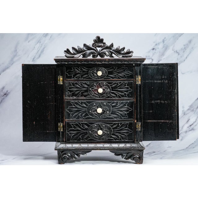 A striking study in old-world craftsmanship, this hand carved wood miniature chest of drawers is a captivating decorative...